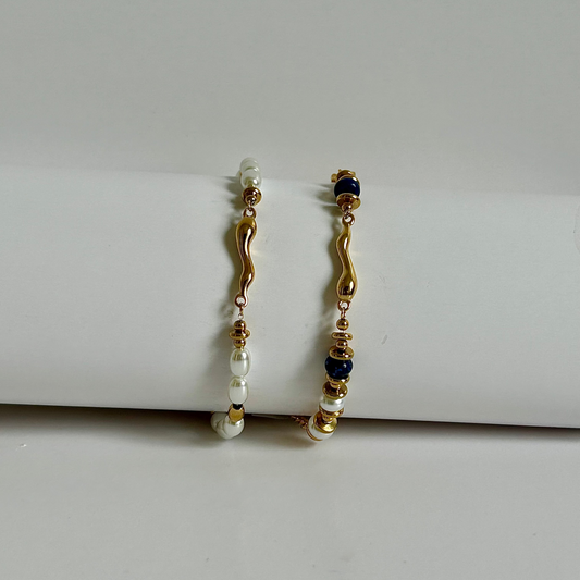 Pair of gold and pearl earrings on a white surface