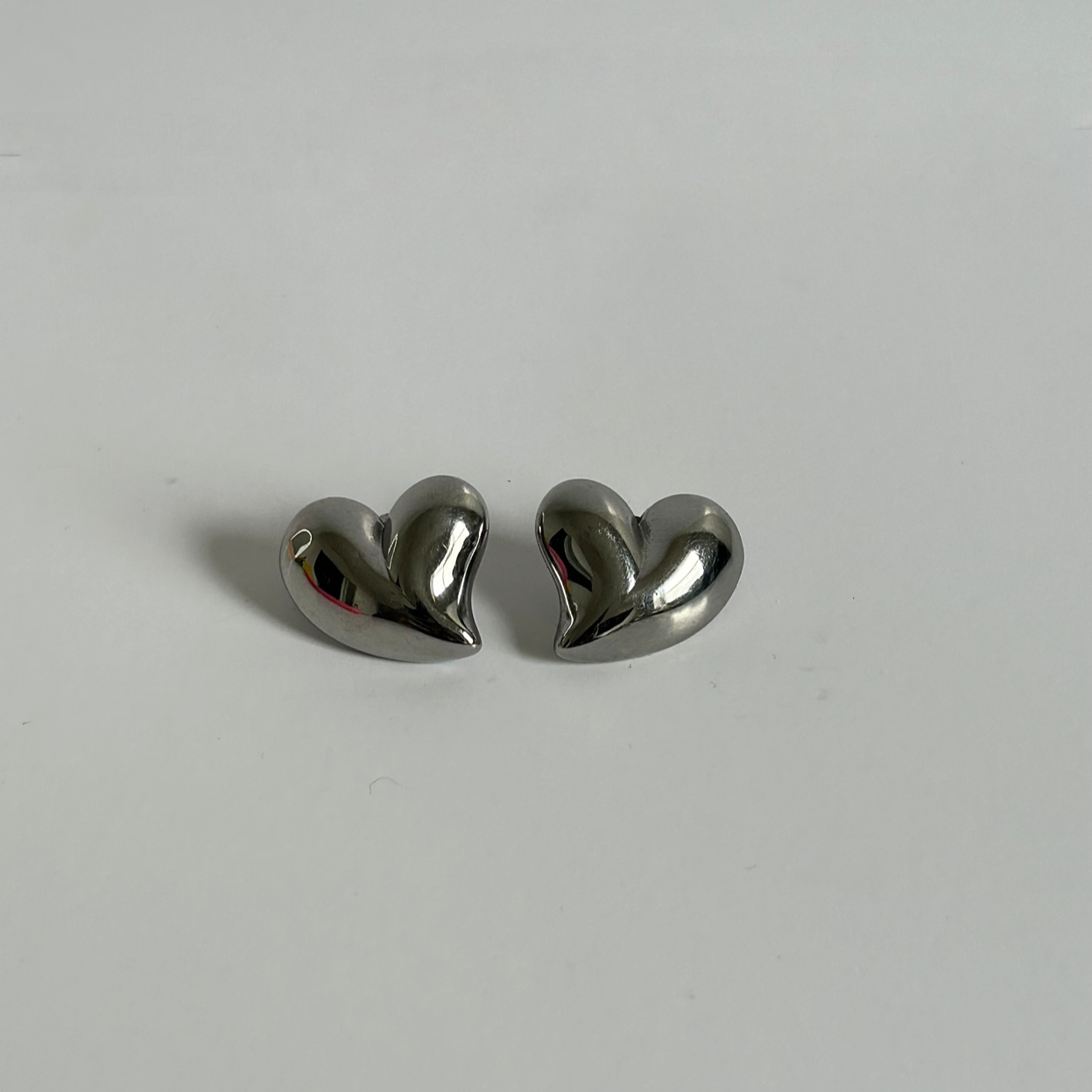 Heart-shaped silver earrings on a light gray background