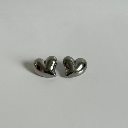 Heart-shaped silver earrings on a light gray background
