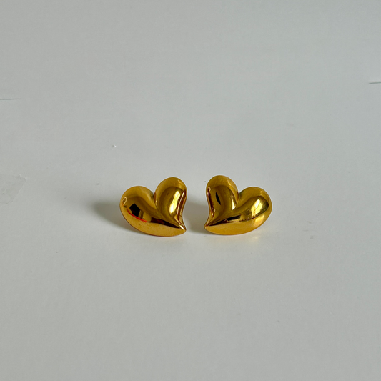 Gold heart-shaped earrings on a light gray background
