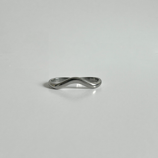 Silver ring with a wavy design on a light gray background