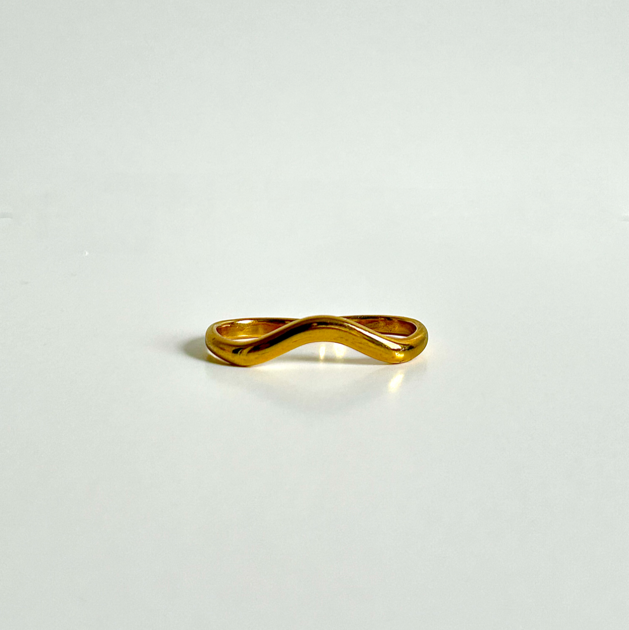 Gold ring with a unique design on a light gray background